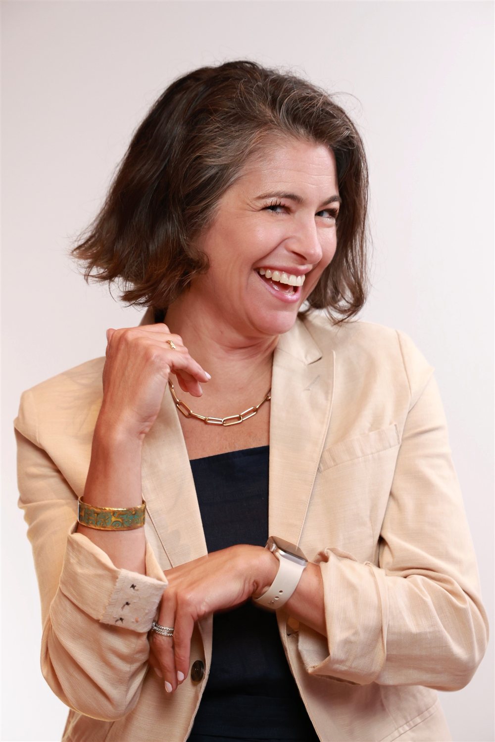 Julie Peller laughing, hand at her necklace